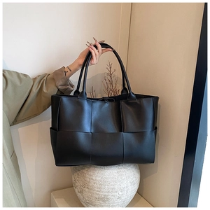 Close-up of black woven leather tote bag featuring oversized Intrecciato weave texture
