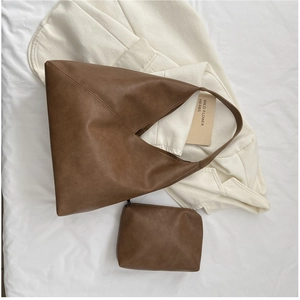 Detailed view of the brown leather tote bag's premium texture and matching pouch