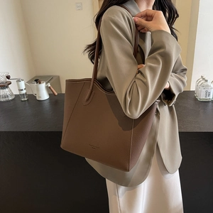 Brown lychee leather tote bag with slim shoulder straps shown on a model in a cafe