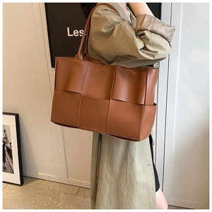 Detail of the oversized brown woven leather pattern on a spacious shoulder tote bag
