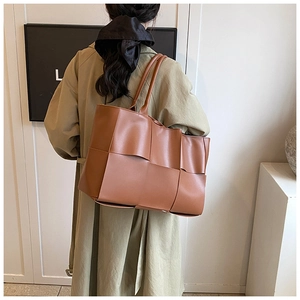 Detailed back view of a model wearing a brown woven leather tote bag for daily commute