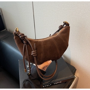 Detail of dark brown matte croissant bag featuring pleated seams and knotted strap detail