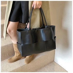 Detailed close-up of large weave pattern on premium black oversized tote bag