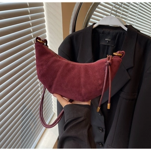 Detail of burgundy matte croissant bag with segmented stitching and metallic zipper