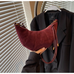 Detail of burgundy suede croissant bag featuring golden zipper and sleek shoulder strap