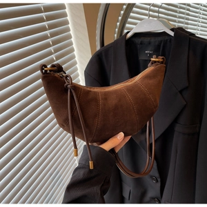 Detail view of dark brown frosted suede croissant bag with vertical stitching and knot charm