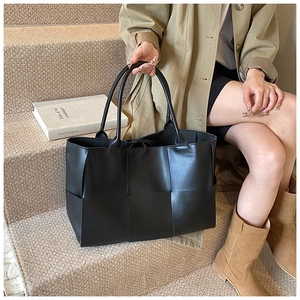 Detail of black woven leather tote bag showing large capacity and textured finish