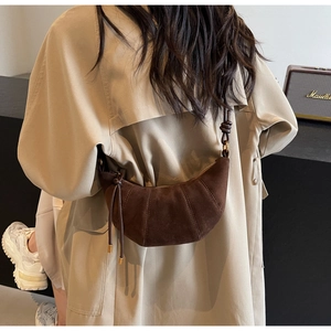 Detail shot of a dark brown suede crescent bag with pleated croissant style texture