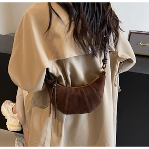 Detail of dark brown matte croissant bag with pleated texture and adjustable strap