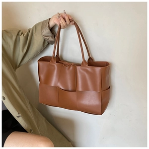 Detail of premium brown leather tote featuring large woven pattern and urban style
