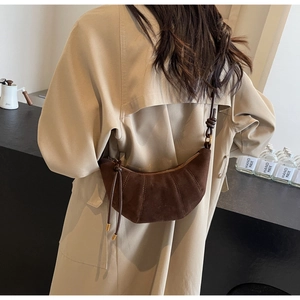 Brown matte suede croissant bag detail worn by a model in a beige trench coat