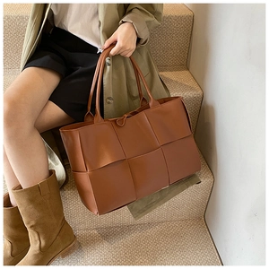Close-up of brown woven leather tote bag with checkerboard texture on a model