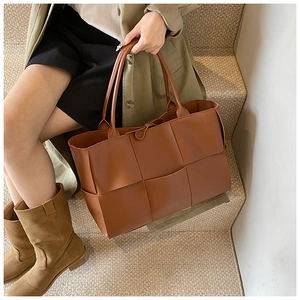 Detail of caramel woven leather tote bag showing large square weave and thin handle