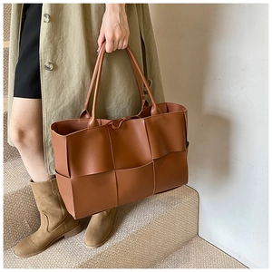 Detail of wide brown leather strips woven pattern on a spacious commuter tote bag