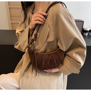 Detail view of dark brown suede crescent bag with knotted shoulder strap and gold hardware