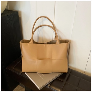 Detailed close-up of large woven tote bag with wide checkerboard pattern in camel brown
