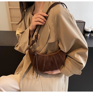 Detail of vintage brown suede crescent bag featuring vertical pleated texture and knotted strap