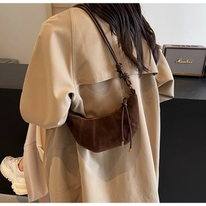 Close-up of deep brown suede croissant bag with pleated details and knotted shoulder strap