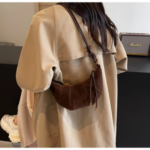 Detail view of brown suede croissant bag with vertical stitching and knotted shoulder strap
