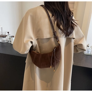 Detail of a dark brown suede croissant bag with knotted strap and minimalist stitching
