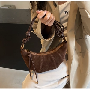 Close-up of dark brown suede croissant bag with stitch detail and knotted leather strap