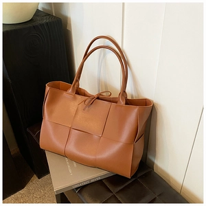 Detail of camel woven tote bag featuring decorative bow and premium leather texture
