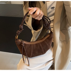 Detail of dark brown matte croissant bag with a knotted shoulder strap and suede texture