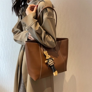 Sac cabas en cuir marron avec surpiqûres blanches et breloque lapin sur mannequin