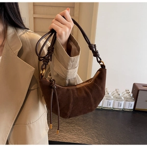Detailed close-up of dark brown crescent bag with suede texture and knotted cord strap