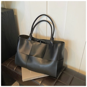 Macro detail of high-quality black leather woven tote bag with wide weave texture