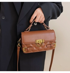 Detail of vintage brown quilted handbag with gold metal buckles and chain strap