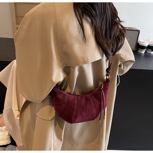Detail of burgundy suede croissant bag showing matte texture and knotted shoulder strap