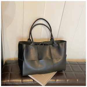 Close-up of premium black woven leather tote bag showing intricate square weave detail