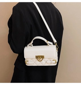 Close-up of white quilted crossbody bag worn over a black blazer for a stylish look