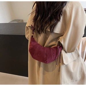 Detail view of burgundy suede croissant bag with stitched seams and gold-tone hardware