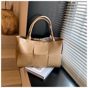 Close-up of large beige woven leather tote bag featuring intricate wide intrecciato pattern