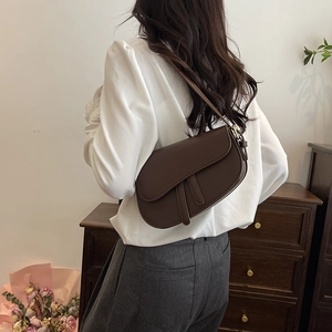 Retro dark brown matte leather saddle bag with gold buckle on a minimalist model