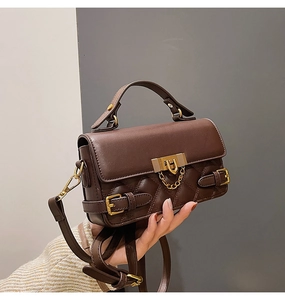 Close-up of a dark brown crossbody bag featuring quilted stitching and golden hardware locks