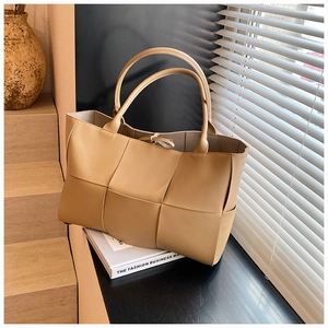 Detail of light tan woven leather tote bag with wide strips and tie closure detail