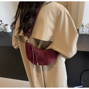 Detail of burgundy suede croissant bag with braided knots and elegant tassels