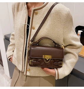 Close-up of a quilted dark brown crossbody bag with gold chain lock and refined texture