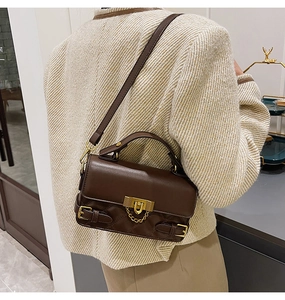 Dark brown quilted leather bag detail worn by a model in a minimalist suit