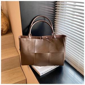 Detail of wide flat weave texture on a large dark brown faux leather tote bag