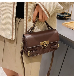 Macro detail of brown quilted leather handbag with gold metal lock and shoulder strap