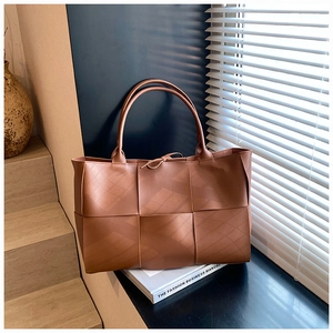 Macro detail of brown woven leather tote bag with elegant bow tie decoration