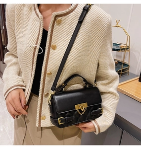 Detail of black quilted crossbody bag featuring gold hardware and a metal buckle on strap