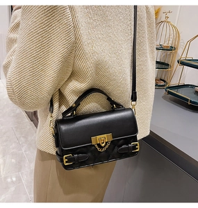 Detailed side view of black quilted crossbody bag with gold hardware and chain lock detail