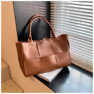 Close-up of caramel woven tote bag detailing the premium leather texture and knotted strap