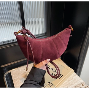 Detailed close-up of burgundy suede croissant bag with stitched texture and knot handle