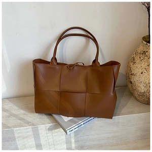 Detailed view of brown woven leather tote bag with large Intrecciato pattern and thin handles